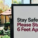 sign cautioning people to remain six feet apart at a shopping mall or retail space for COVID-19 precautions