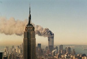 Picture of the Empire State Building in the foreground on September 11th with the buring World Trade Towers in the background