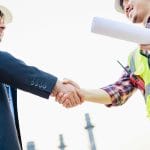 Construction worker and business man in suit shake hands after an in-depth asset search