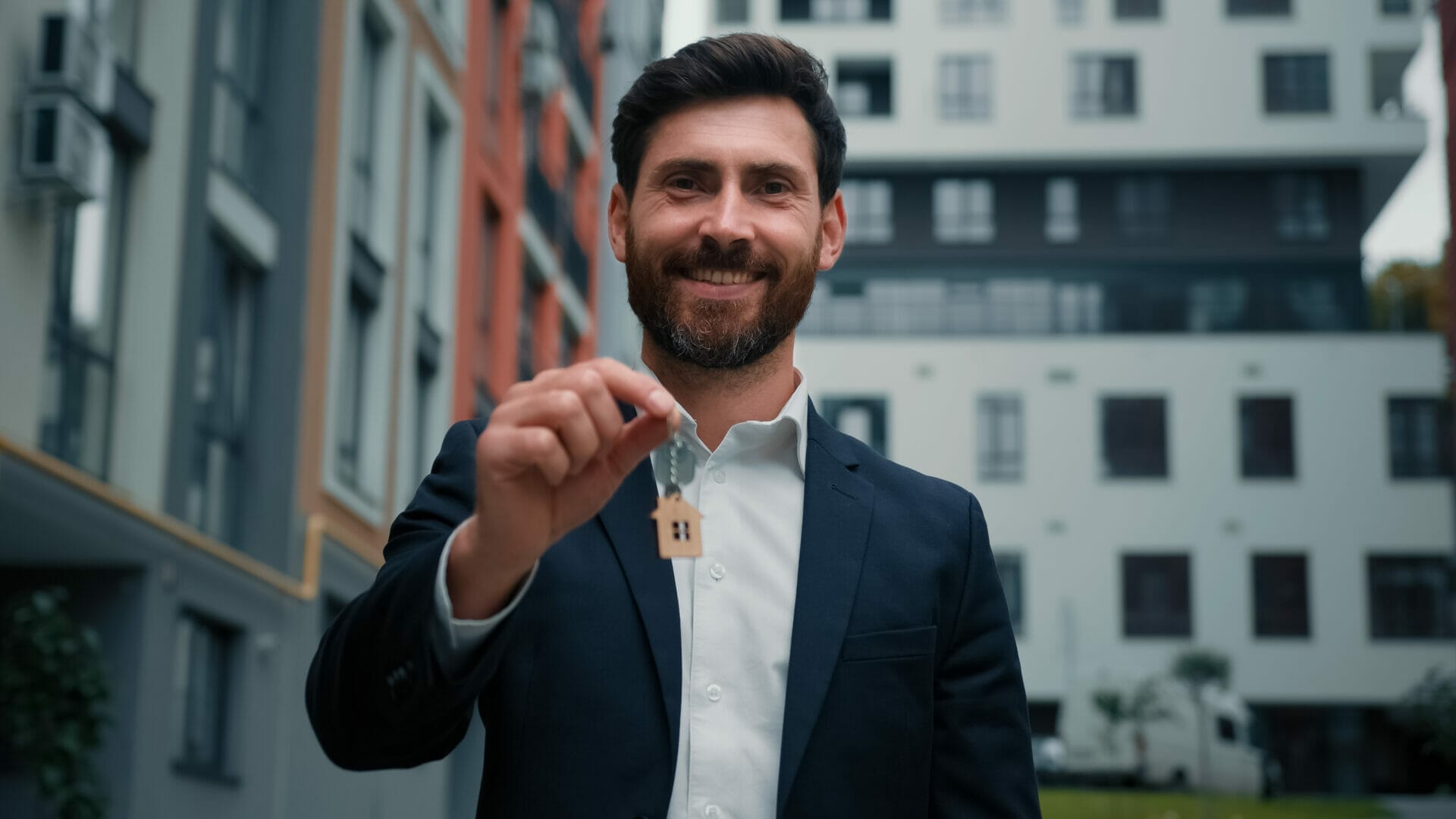 businessman man handing a tenant keys to their new property. How Security Can Help Property Managers Combat High Tenant Vacancy Rates.