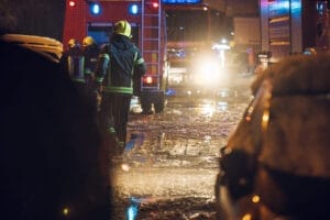 Emergency Response Plans - Firemen near their truck on the street having rest after they put out a fire at night. Emergency , danger, service concept. Firemen at work.