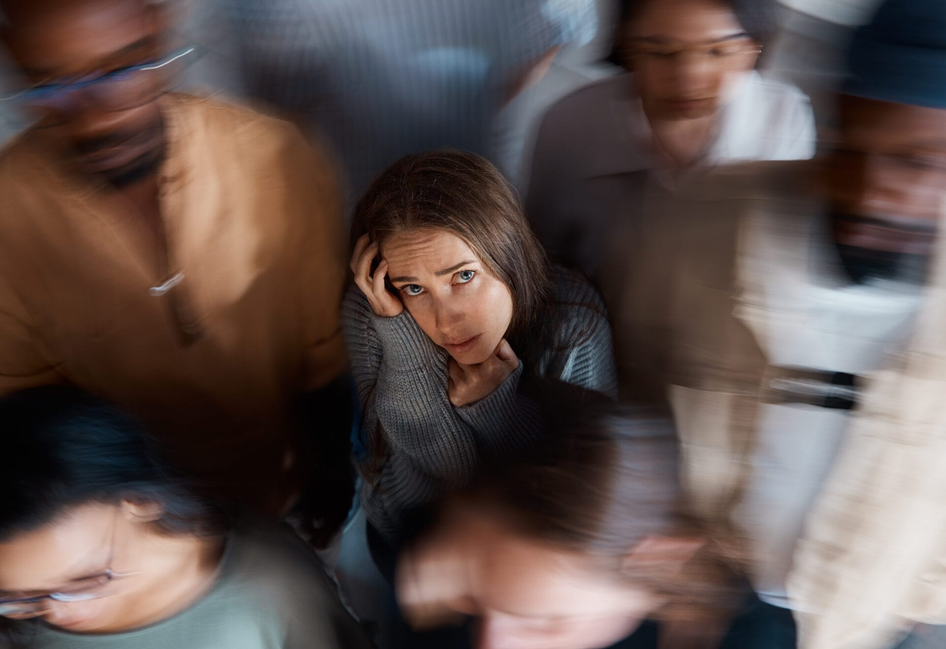 de-escalation training: An image of a young woman at the center of a crowd feeling overwhelmed practicing de-escalation techniques